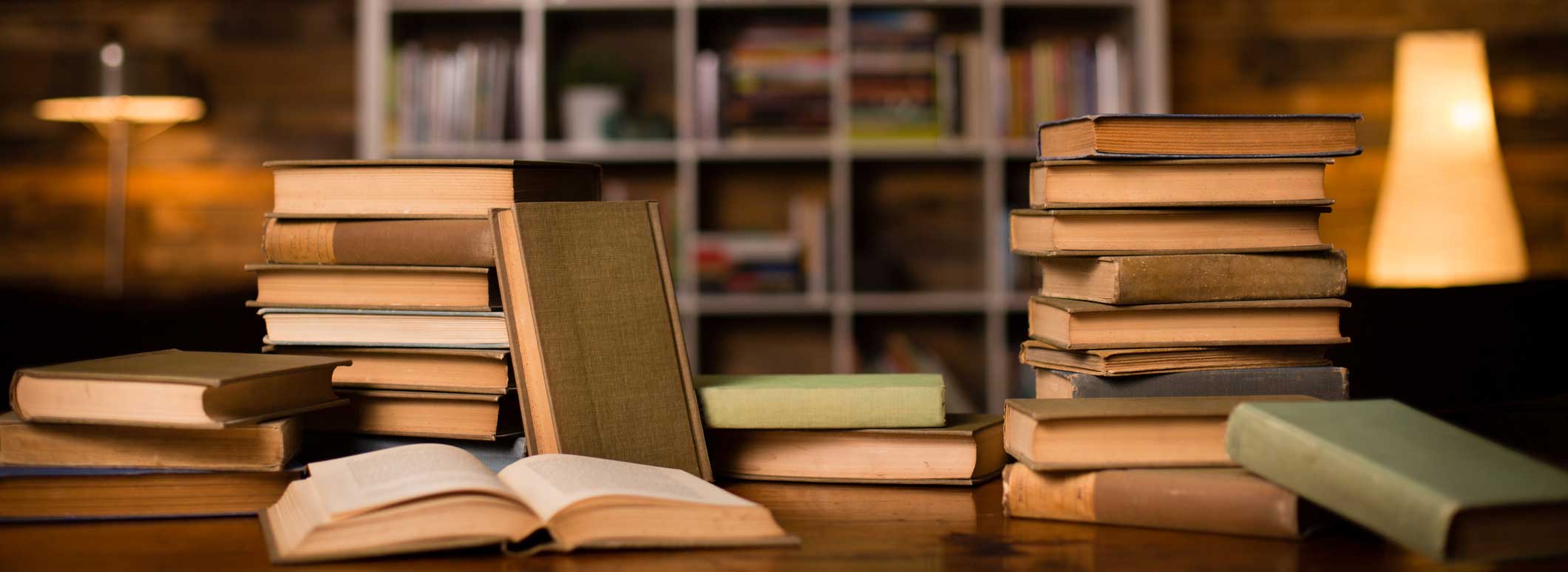 piles de livres sur une table en bois dans une bibliothèque
