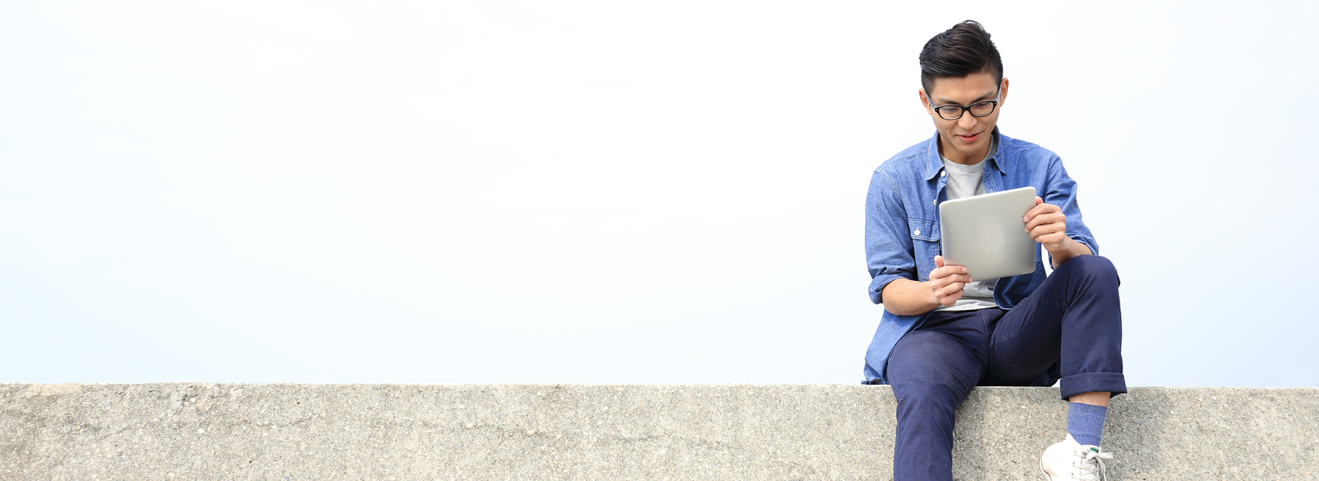 a man sitting on a bench looking at a laptop and he seems happy