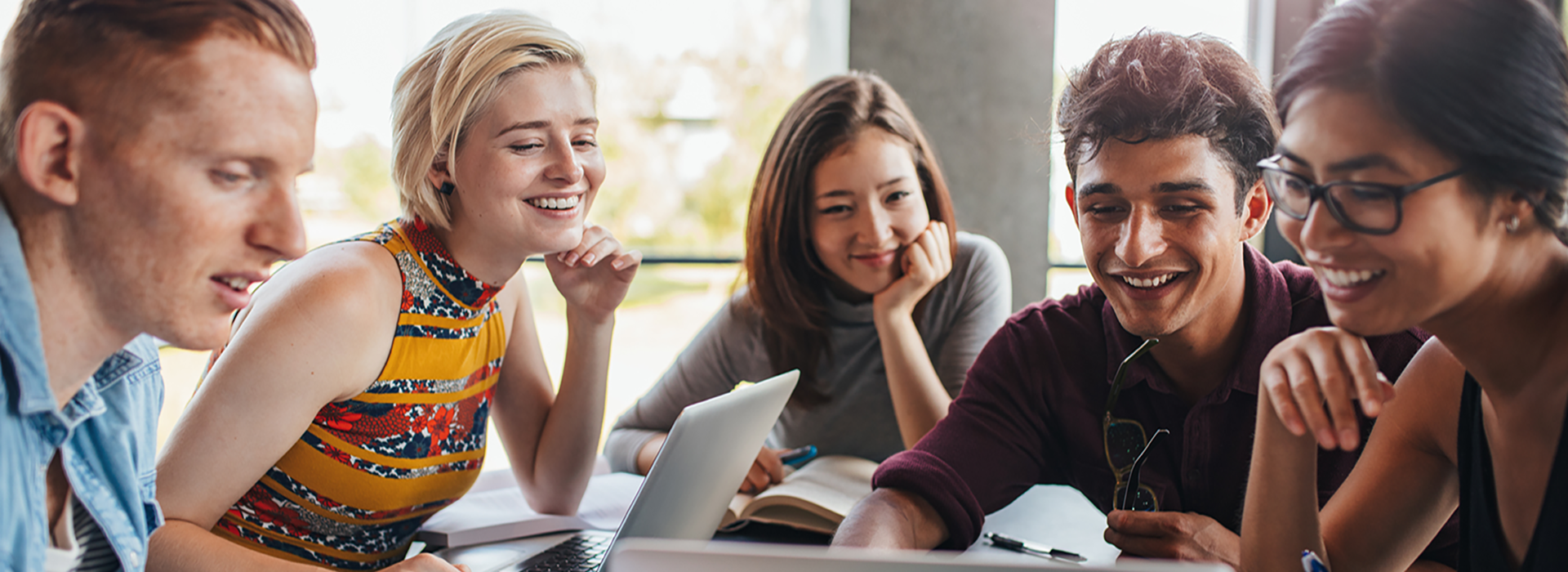 a group of people sitting at a table looking at a laptop and they seem happy