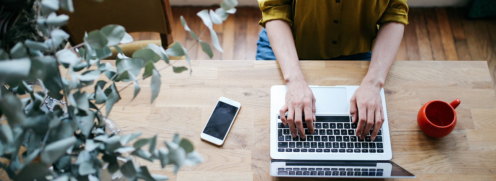 une personne utilisant un ordinateur portable assis sur une table en bois.