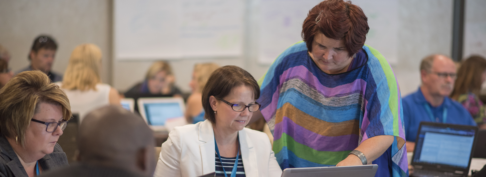 A woman helping another woman in a computer lab