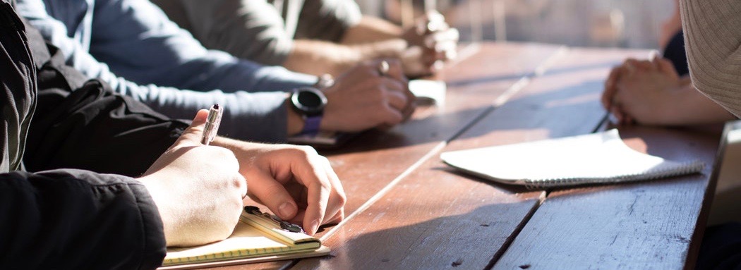 Les mains posées sur une table en bois au soleil.