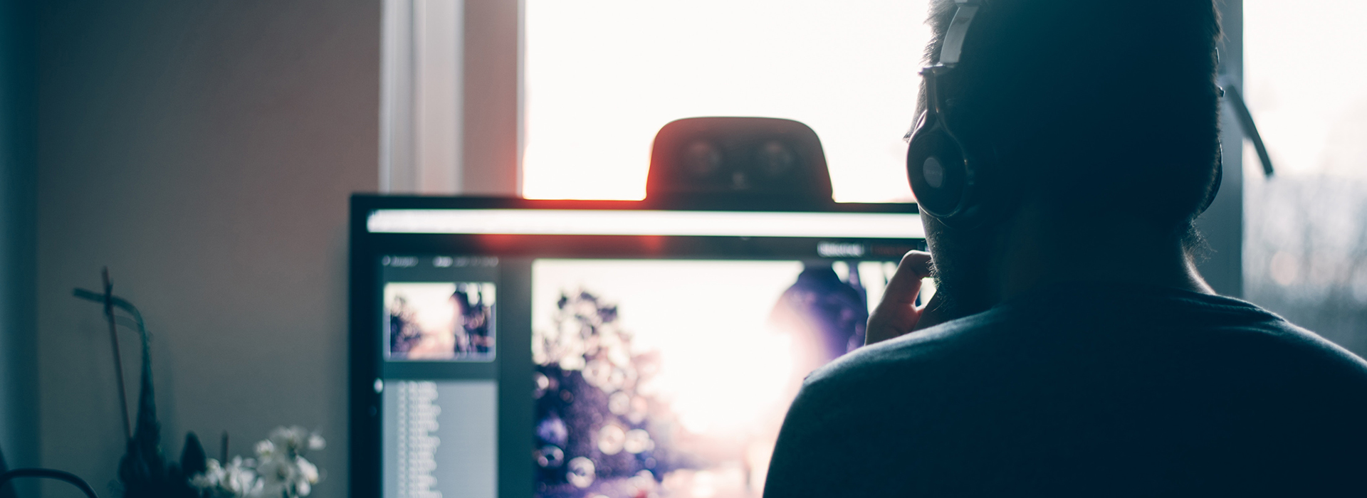 Man wearing headphones editing photos on computer.