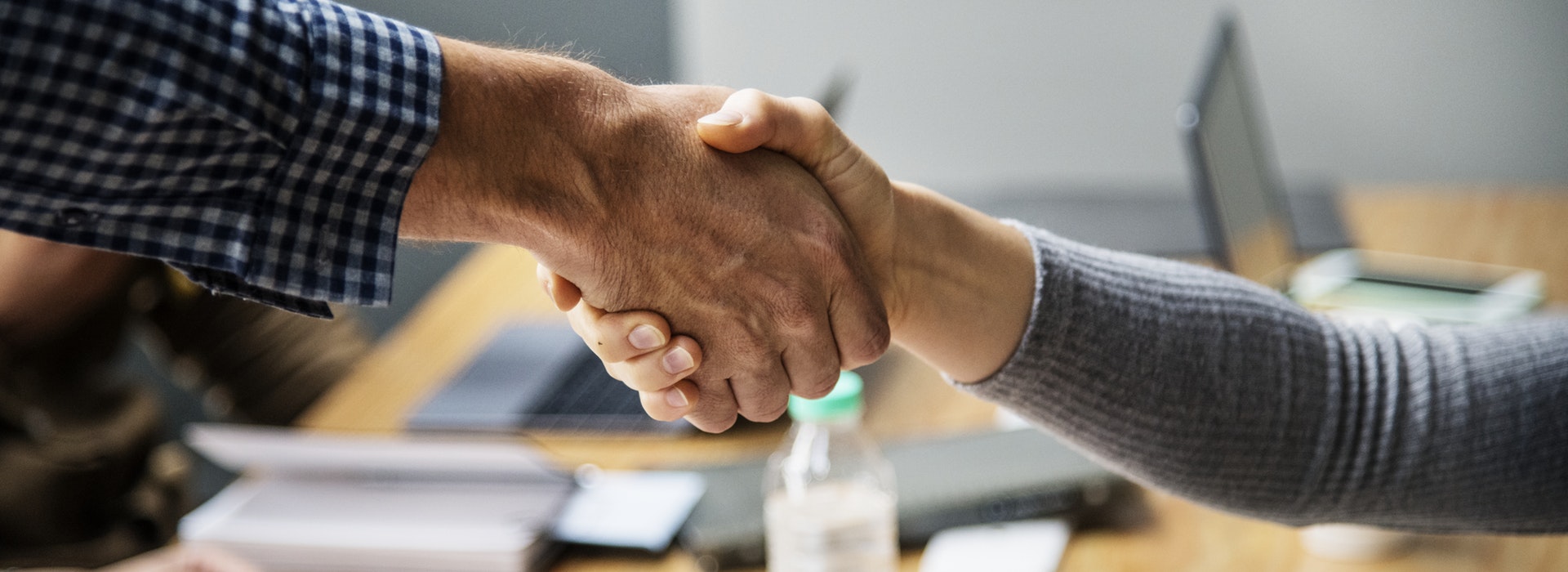 Two people shaking hands across a desk