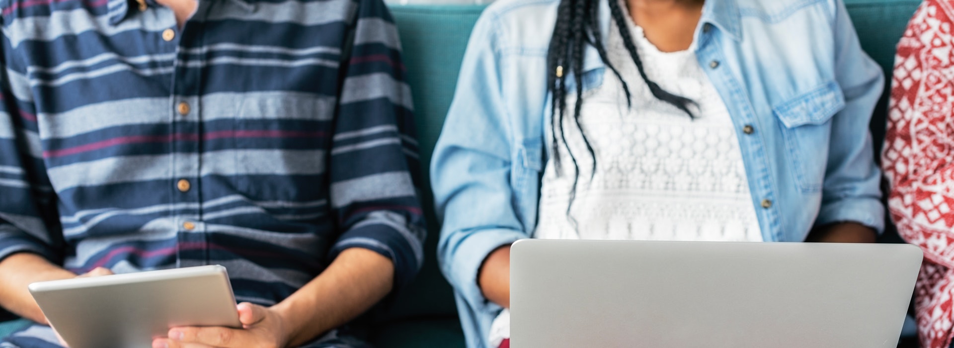 Two students sit beside each other, both using laptops