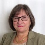 Headshot of a woman with shoulder-length brown hair and glasses