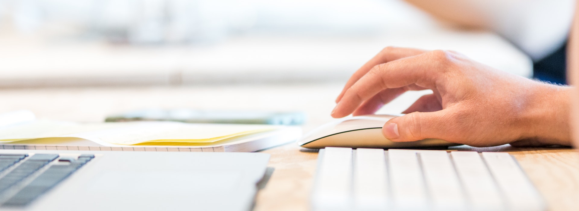 Closeup of a hand touching a white keyboard and mouse