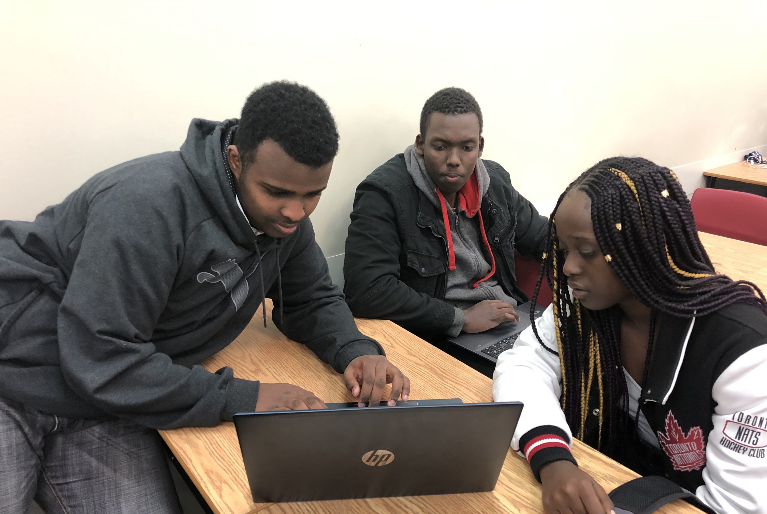 trois étudiants aux cheveux noirs regardent un ordinateur portable