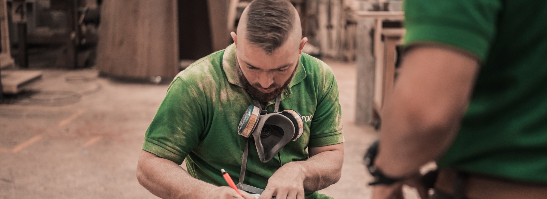 Photo of a male construction worker in a green shirt signing some paperwork