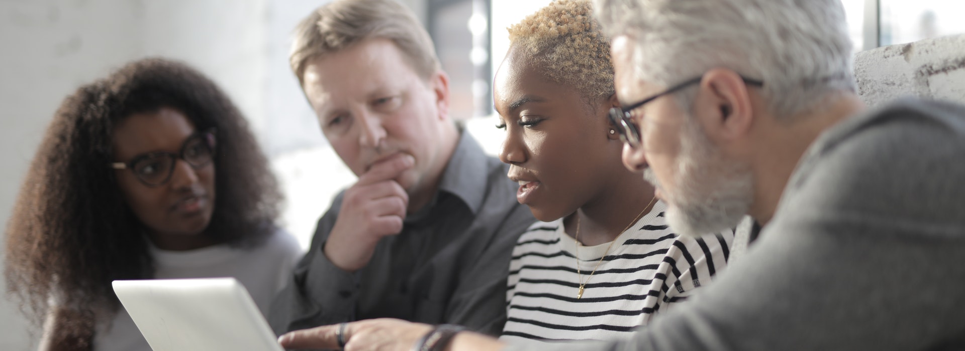 A group of professionals look at a laptop together