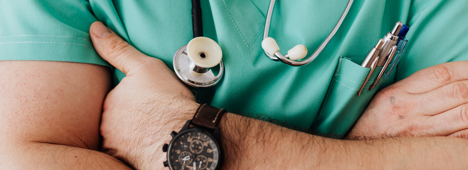 closeup photo of man’s torso wearing green medical scrubs